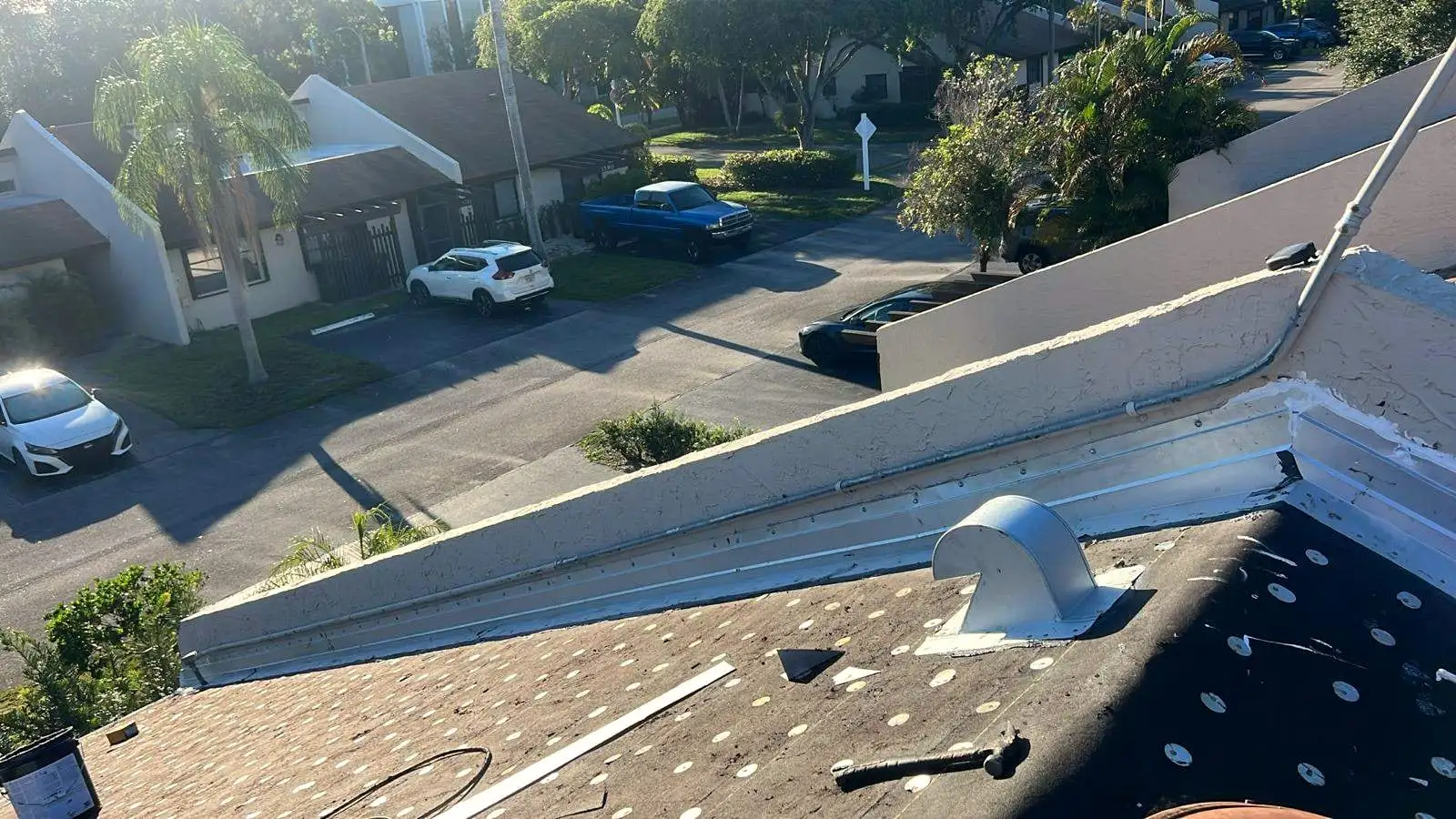 Metal flashing along a stucco parapet wall and a roof vent on a low-slope roof