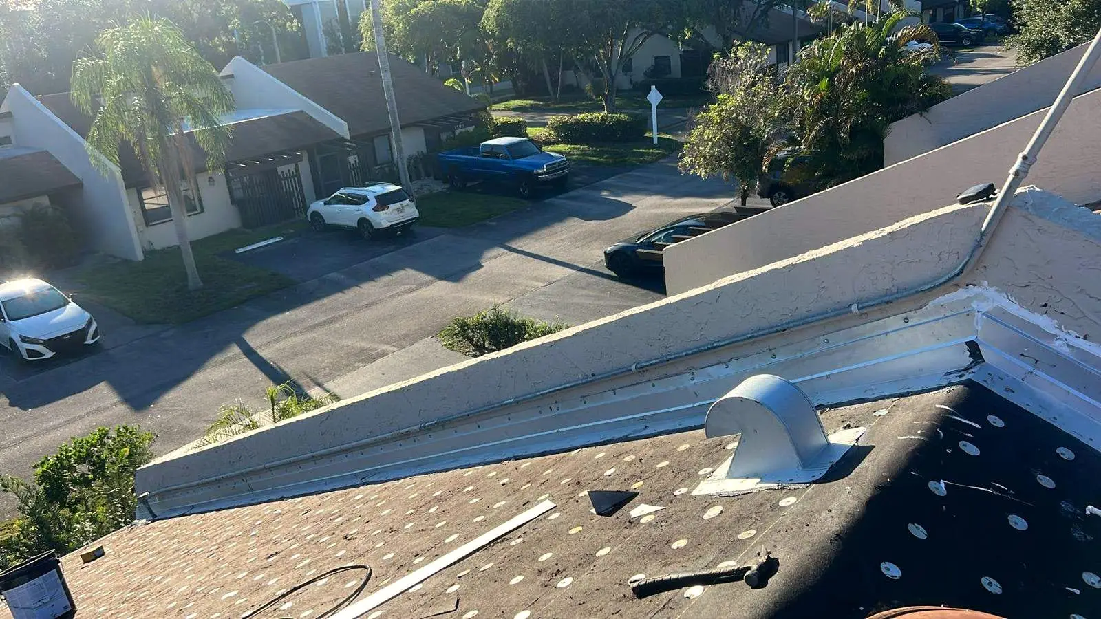 Metal flashing along a stucco parapet wall and a roof vent on a low-slope roof